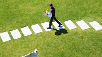 A person walking across a grassy area with white rectangular markings.