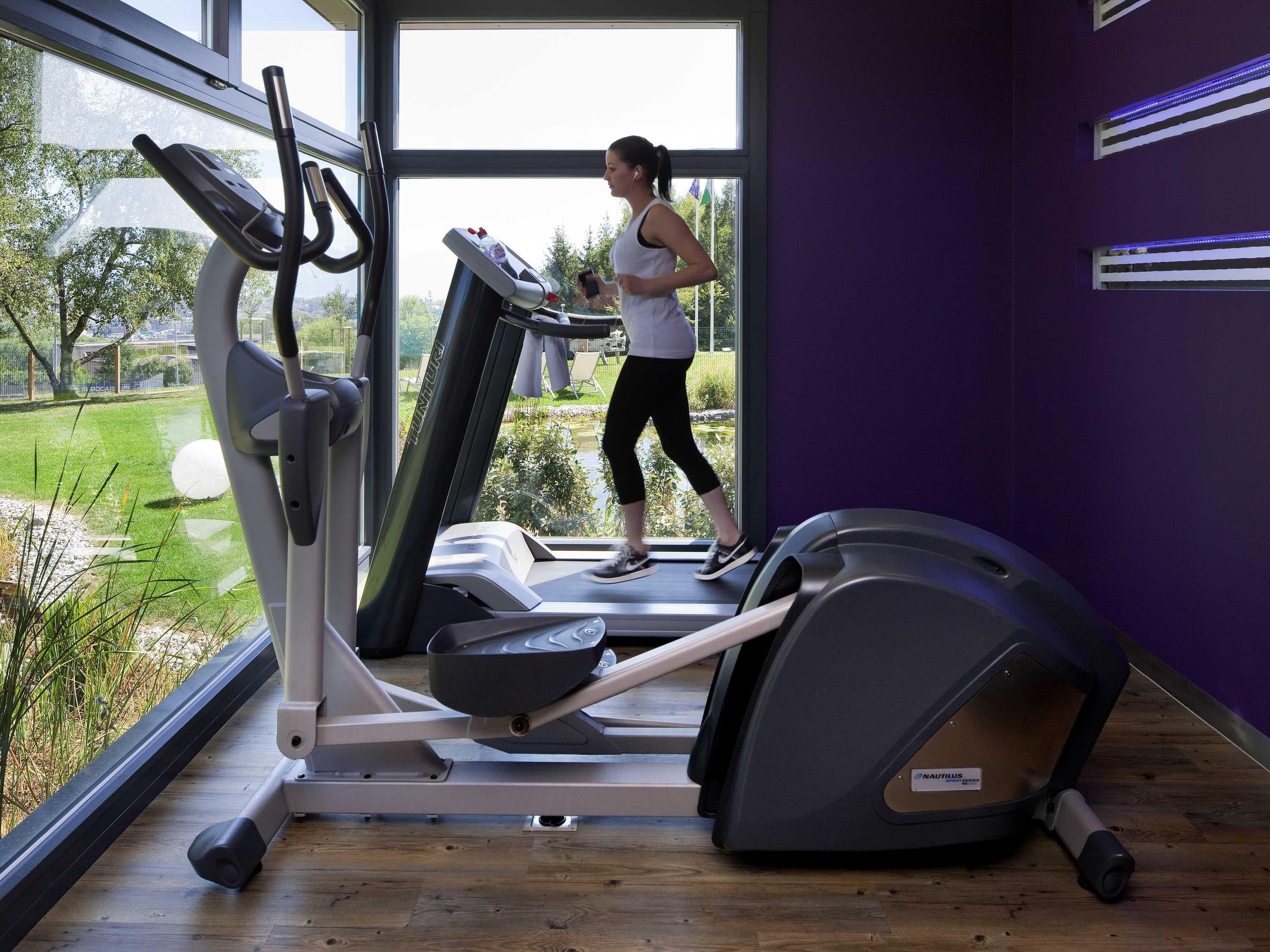 Ein Fitnessraum mit Laufbändern, Fahrrädern und einem Rudergerät.