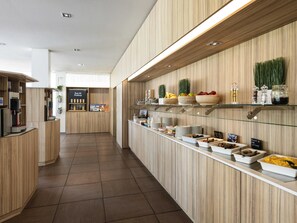 A modern breakfast bar with wooden paneling, a coffee machine, and various food items displayed on shelves.