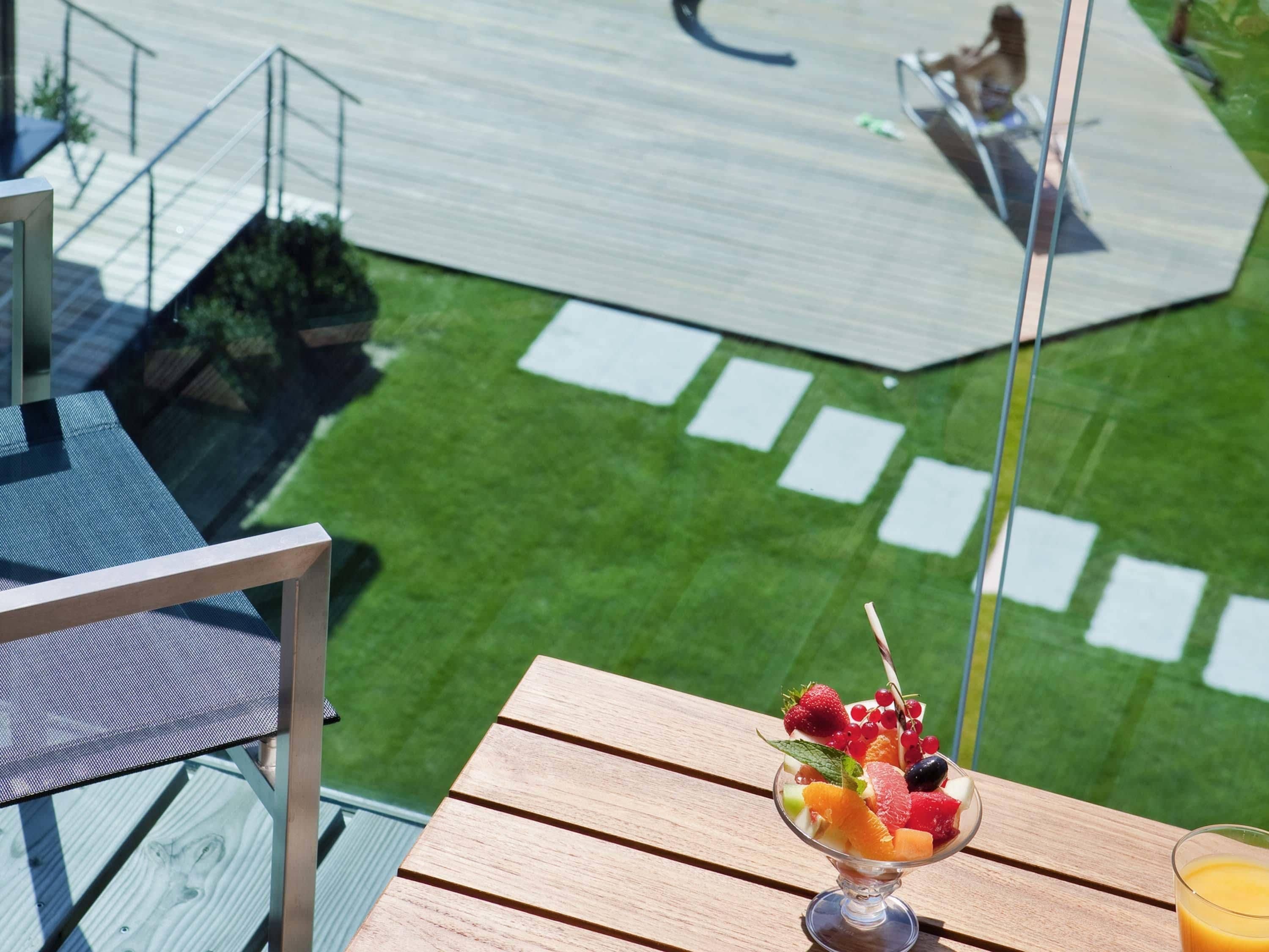 Ein Balkon mit Tisch, Orangensaft und einem Obstdessert.