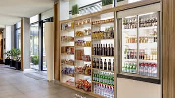 Un espace de vente au détail avec des étagères remplies de divers produits, un rayon réfrigéré contenant des boissons et une enseigne indiquant « MINI MARCHÉ BY NOVO ».
