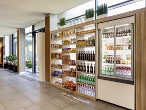 Un espacio comercial con estantes llenos de diversos productos, una sección refrigerada con bebidas y un cartel que dice 'MINI MARKET BY NOVO'.