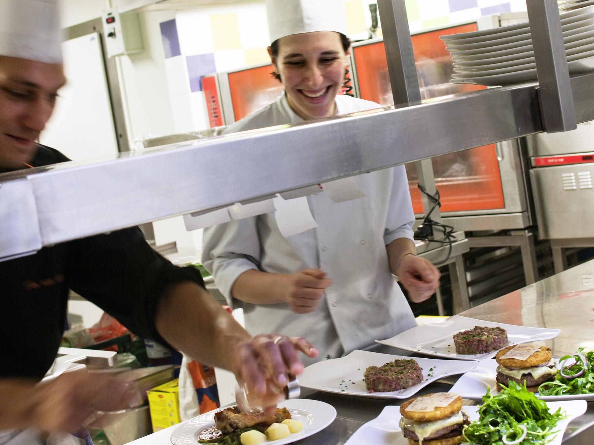 A kitchen with chefs preparing food, stainless steel appliances, and a clean, organized workspace.