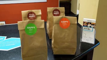 A counter with three brown paper bags labeled "HAPPY KIT" and "HAPPY FUEL" from Hampton.com.