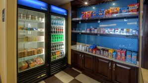 Ein Selbstbedienungsbereich mit Snacks und Getränken, der gekühlte und ungekühlte Produkte sowie eine Auswahl an Speisen und Getränken bietet.