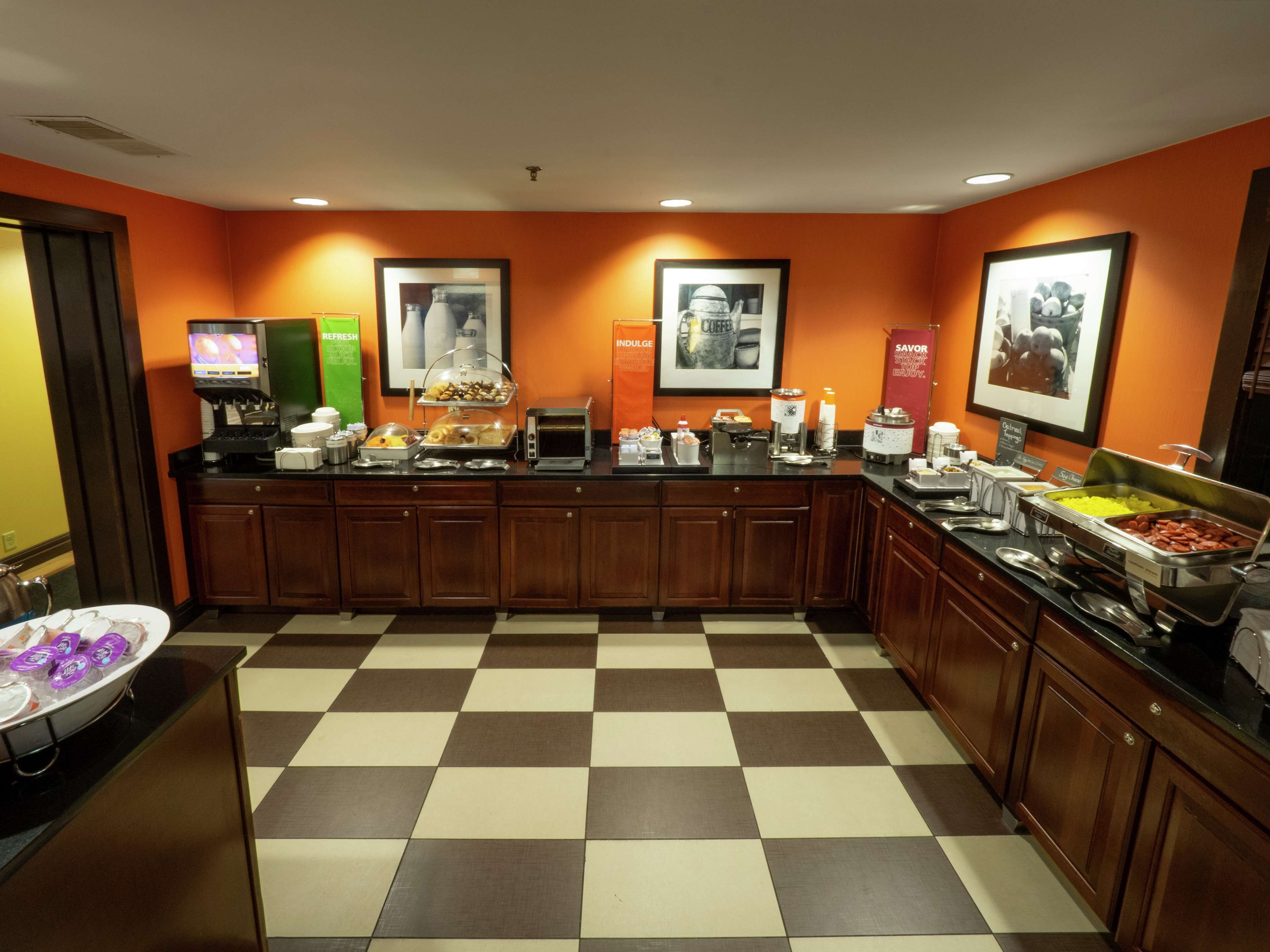 A buffet area with a checkered floor, wooden cabinets, and various food and beverage stations.