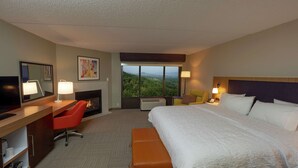 Ein Hotelzimmer mit einem großen Bett, einem Schreibtisch mit Stuhl, einem Fernseher, einem Kamin und Blick ins Freie.