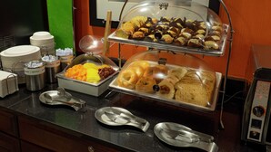 Ein reichhaltiges Buffet mit verschiedenen Speisen, Geschirr und einer Kaffeemaschine.