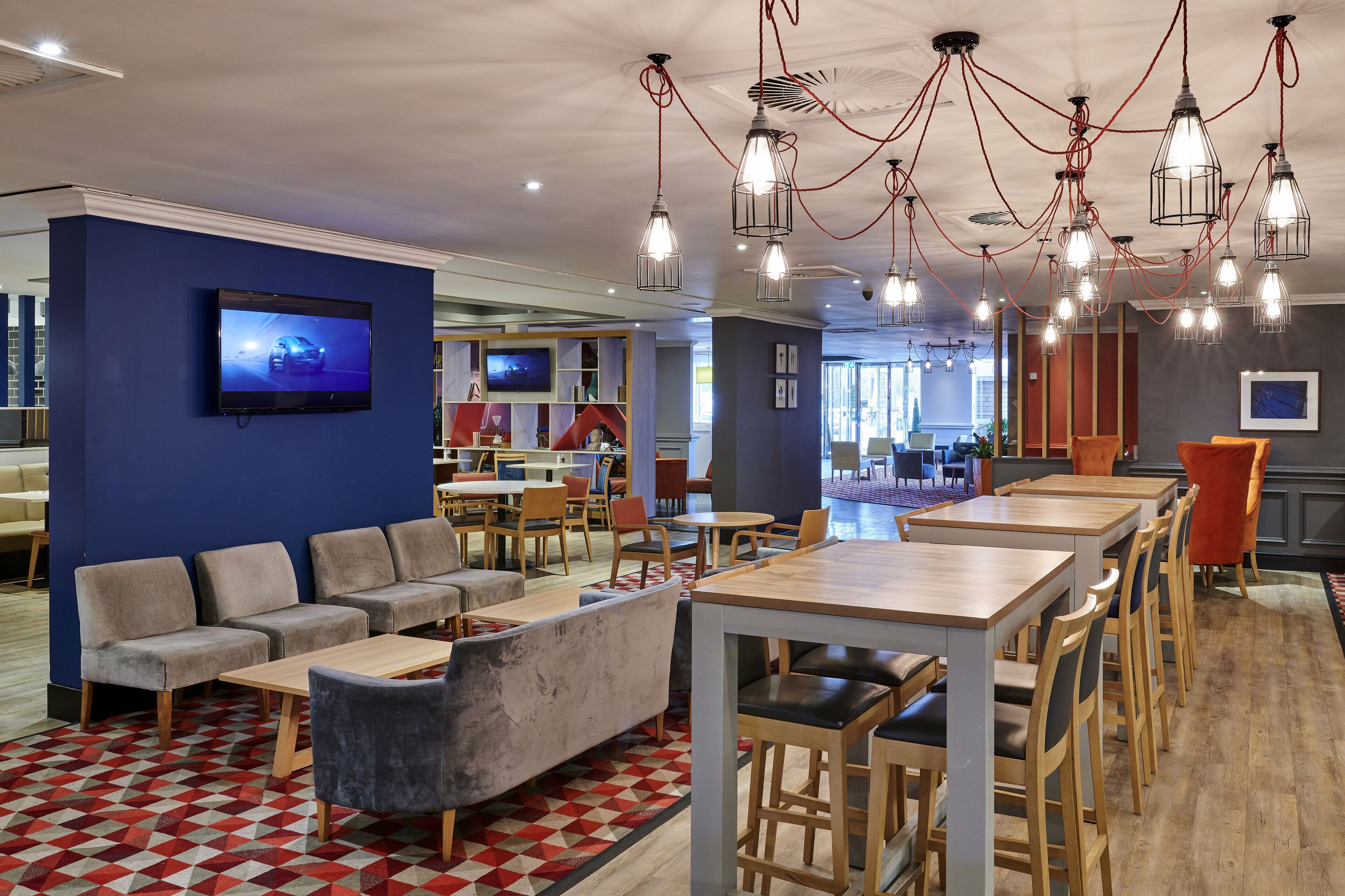 Un espace de détente moderne, avec des canapés, des tables et un écran de télévision.