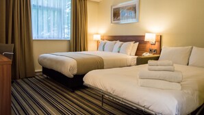 A hotel room with two beds, a window with curtains, a painting on the wall, and a bedside table with a lamp. - Holiday Inn Leeds Garforth by IHG (Leeds)