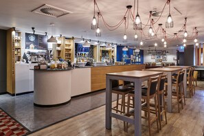 Una Starbucks moderna con una estación de baristas, área de asientos y diversos productos Starbucks a la vista.