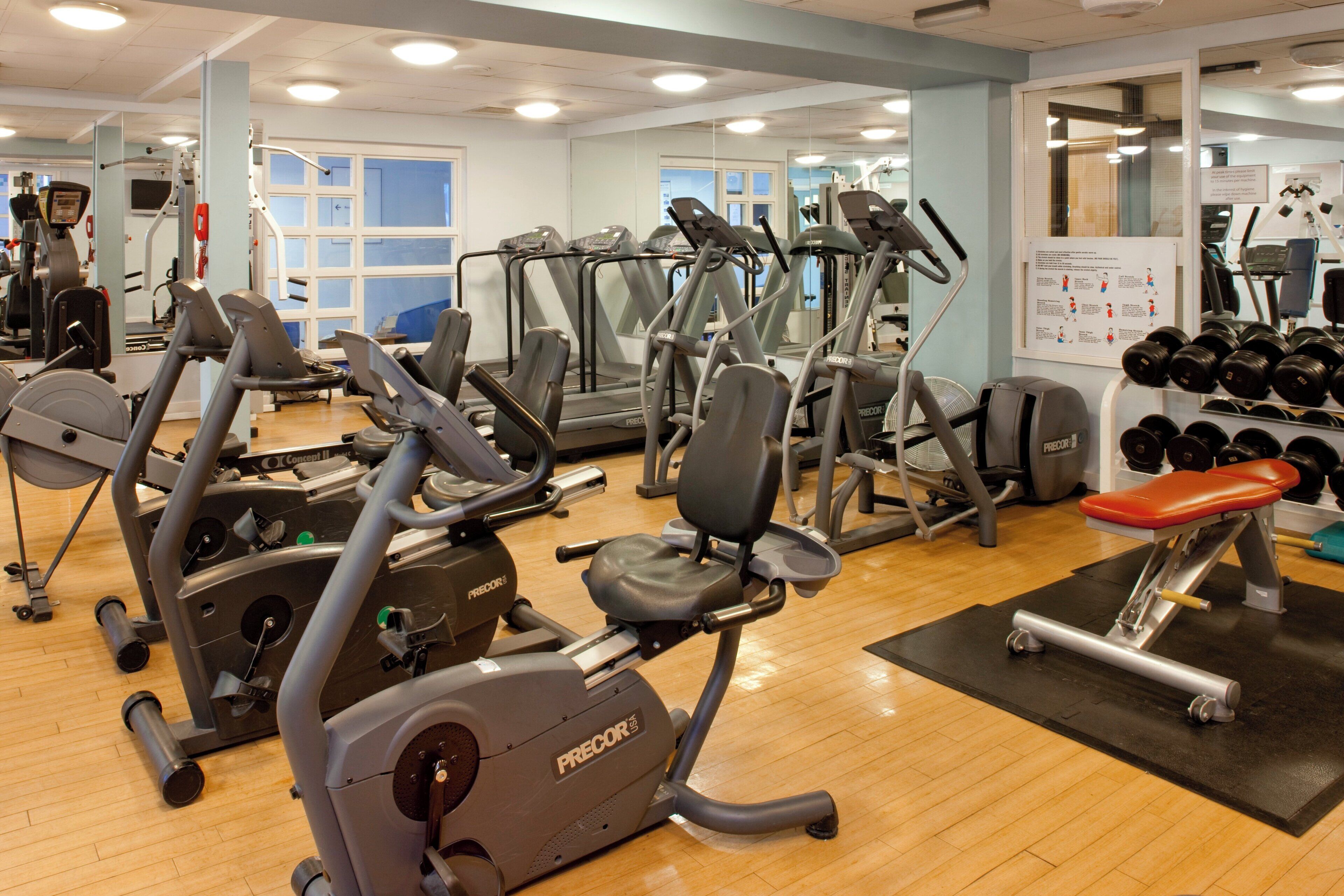 A gym with various exercise equipment including treadmills, stationary bikes, and weight machines.