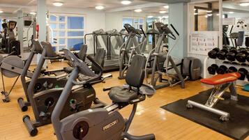 A gym with various exercise equipment including treadmills, stationary bikes, and weight machines.