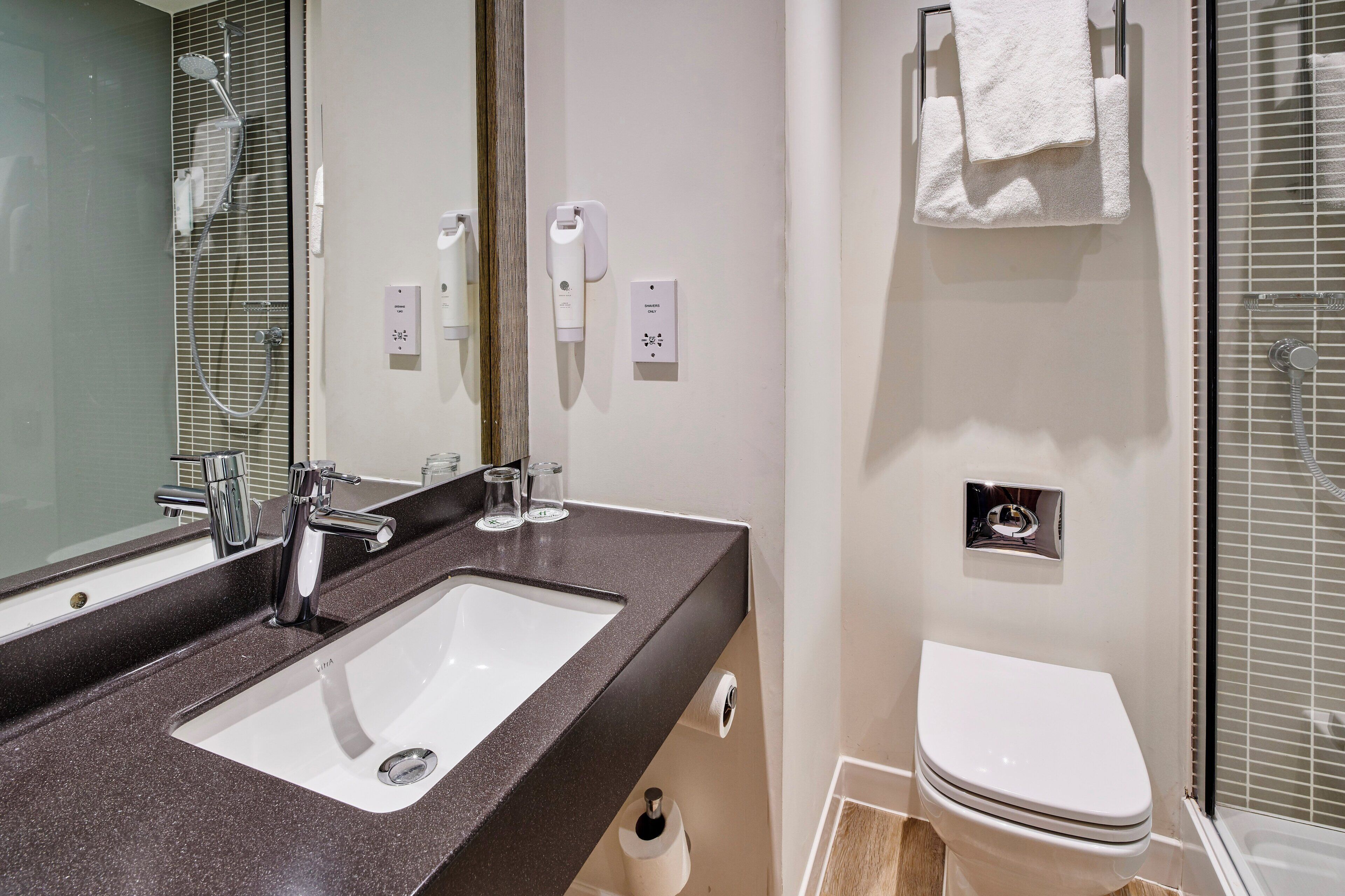 Une salle de bain moderne avec un double vasque, des toilettes et un espace douche.