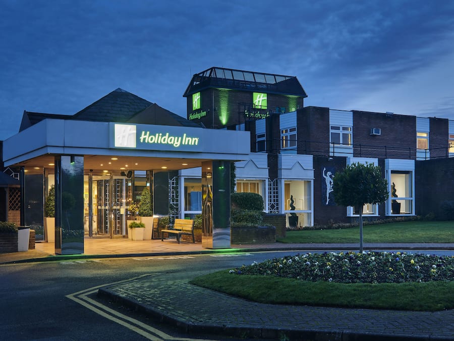 A Holiday Inn hotel with a modern design, featuring a prominent entrance and a rooftop structure.