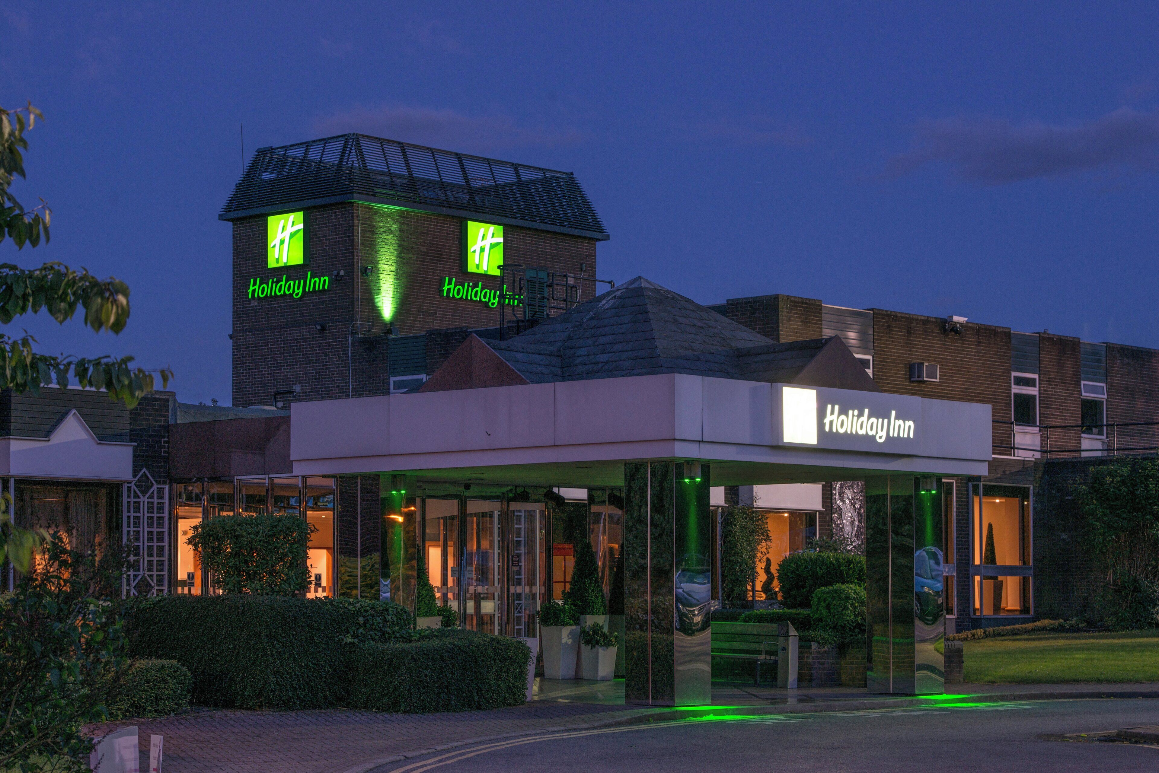 A Holiday Inn hotel with a modern facade, large glass windows, and a prominent sign.