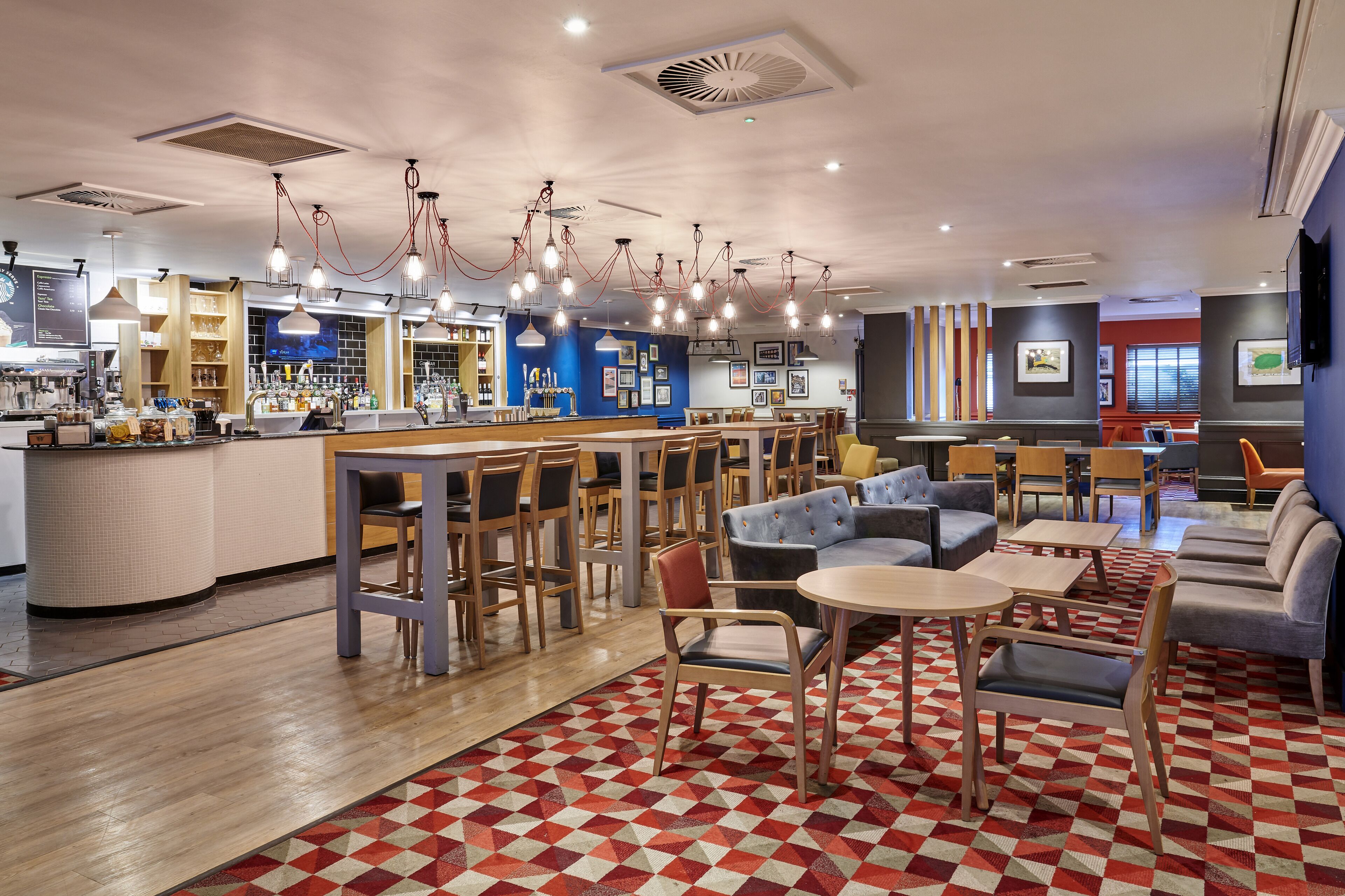 A modern cafe with a bar area, seating arrangements, and a patterned floor.