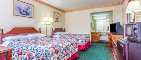 Una habitación de hotel con dos camas, un aparador, un televisor y un espejo.