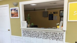 Un espace d’accueil comprenant un comptoir de réception, une porte, un panneau fixé au mur et un paillasson orné du logo « Day Inn ».