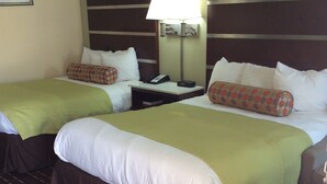 Une chambre d’hôtel avec deux lits, une table de chevet, une lampe et un téléphone.