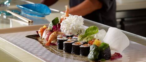 A sushi dish on a table with a chef in the background.