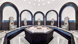 A luxurious bathroom with a central marble sink, multiple toilets, and decorative statues. - Divan Istanbul (Istanbul)