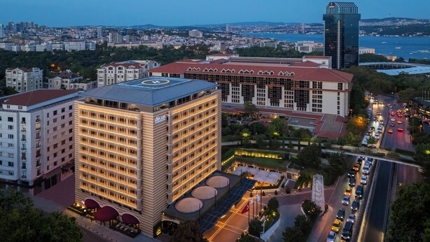 A multi-story hotel with a prominent 'divan' sign, surrounded by other buildings and a busy road with vehicles. - Divan Istanbul (Istanbul)