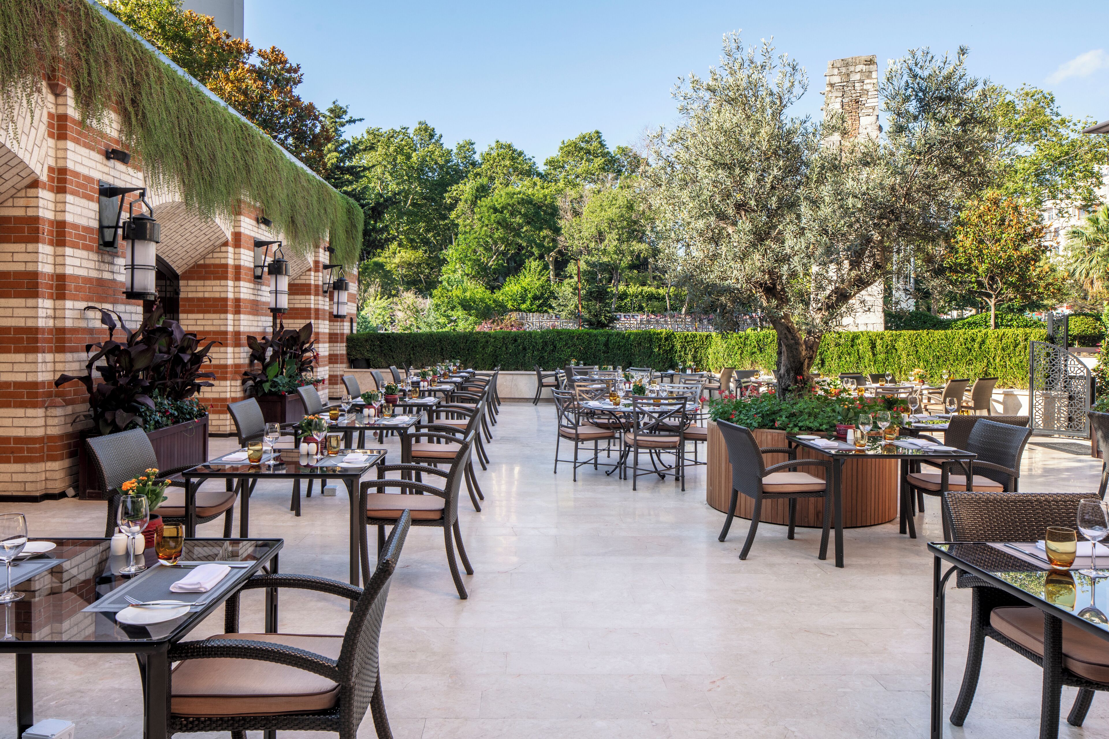 Un área de comedor al aire libre con paredes de ladrillo, mesas y sillas.