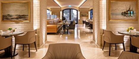 A spacious hotel lobby with high ceilings, a central seating area, and artwork on the walls.