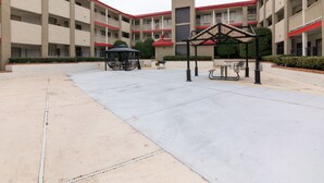 A courtyard with a gazebo, picnic tables, and a building with multiple balconies. - Studio 6 Irving, TX – DFW North (Irving)