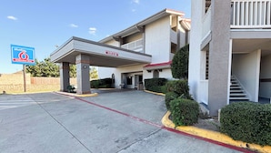 A hotel with a covered entrance, a sign for Studio 6 Extended Stay, and a clear sky. - Studio 6 Irving, TX – DFW North (Irving)