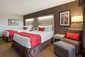 A hotel room with two beds, a chair, a nightstand, and a lamp. - Coast Calgary University Area Hotel by APA (Calgary)