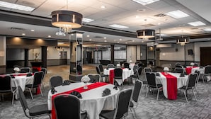 A conference room with round tables, black chairs, and red table runners. - Coast Calgary University Area Hotel by APA (Calgary)