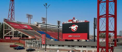 A stadium with a large digital scoreboard, seating areas, and a prominent red tower structure.