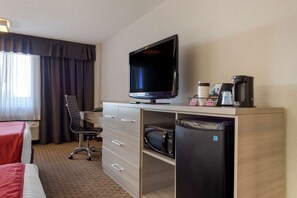 A hotel room with a bed, a desk with a computer, a television, a microwave, and a refrigerator. - Coast Calgary University Area Hotel by APA (Calgary)