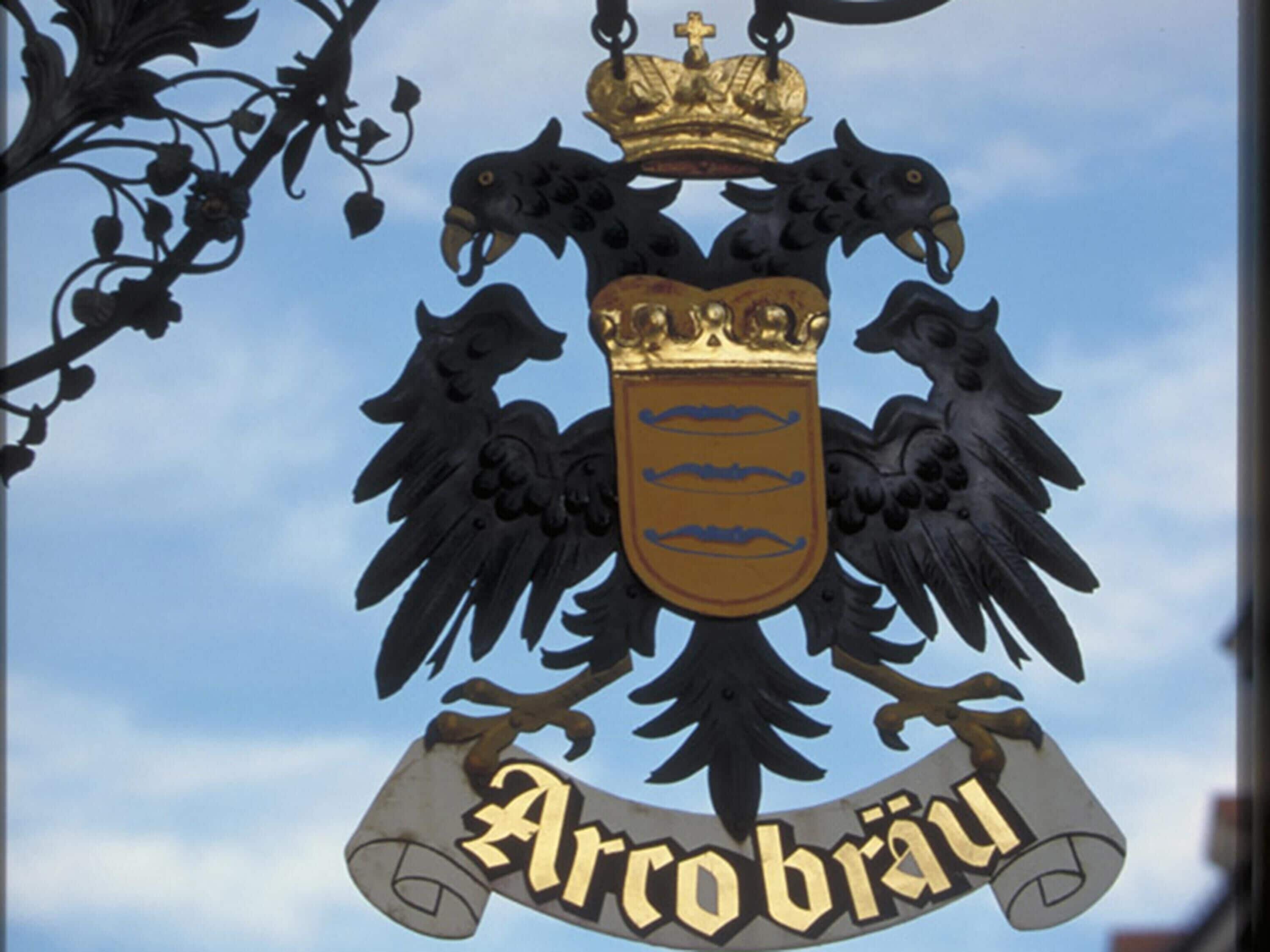 A coat of arms with a crown and two eagles, and the word "ArcoBräu" below.