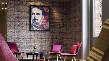 Un área de descanso moderna con una pared estampada, un retrato enmarcado y asientos mullidos.