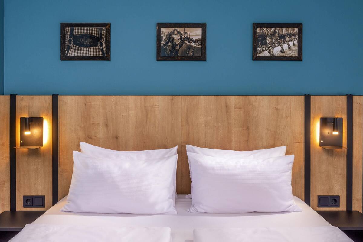 A bed with white linens, a wooden headboard, and three framed pictures on the wall.