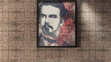 Una habitación con dos sillones tapizados en rojo, una mesa redonda de madera con un jarrón de flores y un retrato enmarcado en la pared.