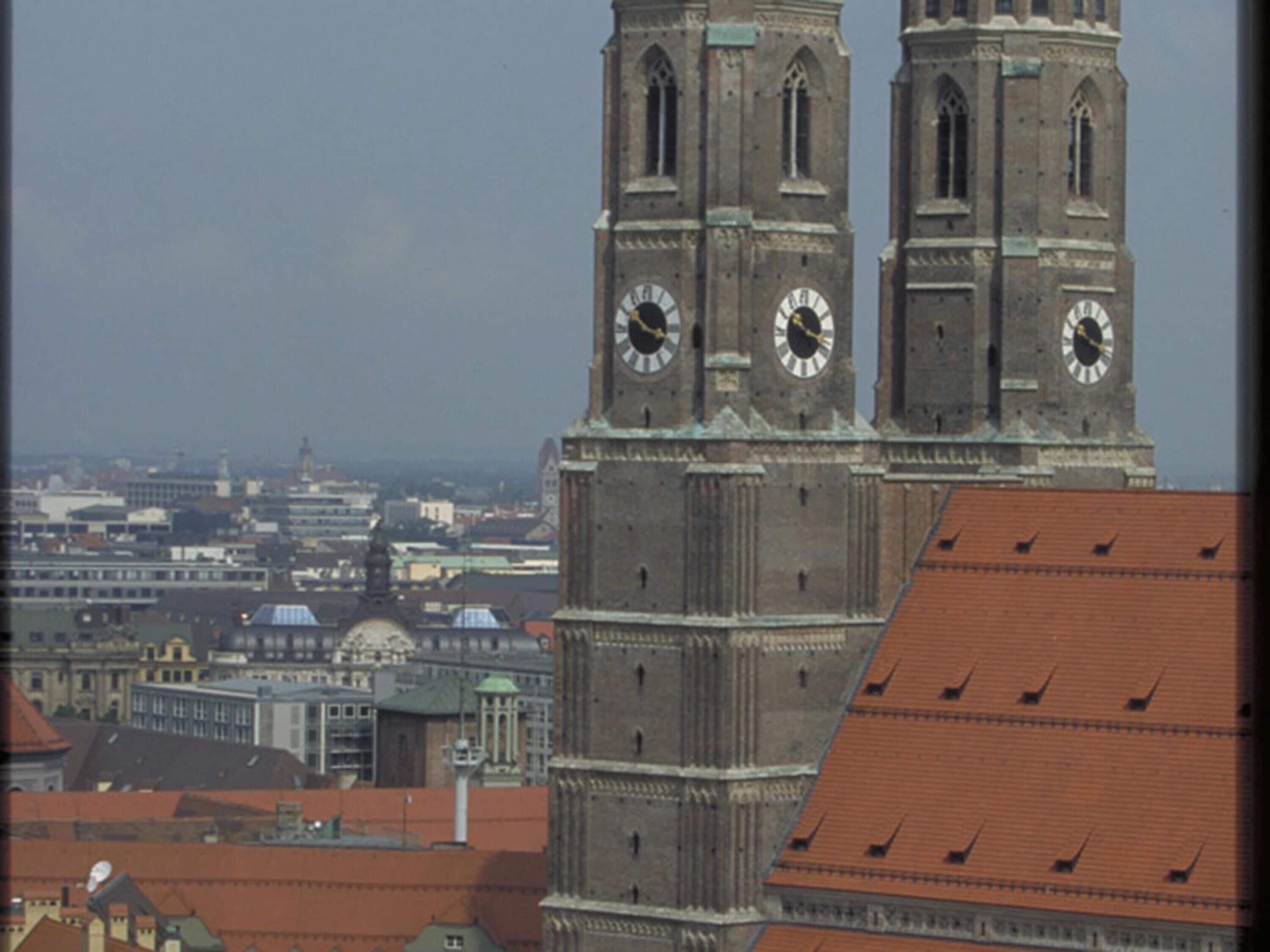 A historic building with two prominent clock towers and a red-tiled roof.