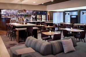 A modern bar area with a counter, seating, and a bar stocked with various beverages.