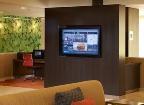 A modern hotel lobby with a digital display, a reception desk, and a comfortable seating area. - Courtyard by Marriott Detroit Metropolitan Airport Romulus (Romulus)