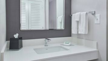 Un bagno moderno con un lavandino bianco, uno specchio e un portasciugamani.