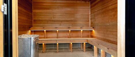 A sauna with wooden benches and a metal heater.