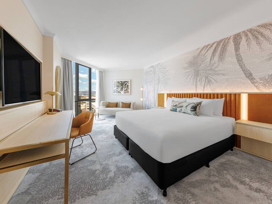 Una habitación de hotel moderna con una cama grande, un escritorio, una silla y una televisión.