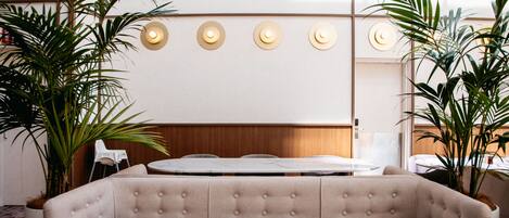 A modern dining area with a marble table, cushioned booth seating, and ambient lighting.