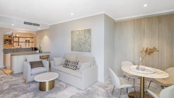 A modern living room with a sofa, coffee table, and dining area with chairs and a table.