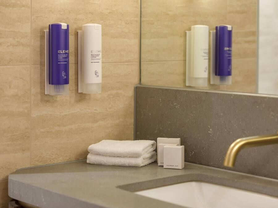 A bathroom with a sink, a towel, and toiletries on the wall.
