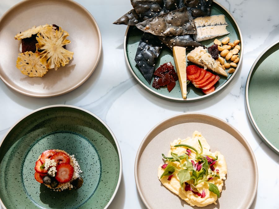 A variety of dishes on plates, including cheese, nuts, and fruits.