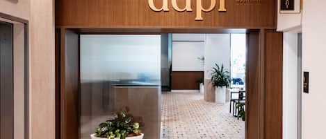 A modern reception area with a wooden sign reading "dapi" and a reception desk.